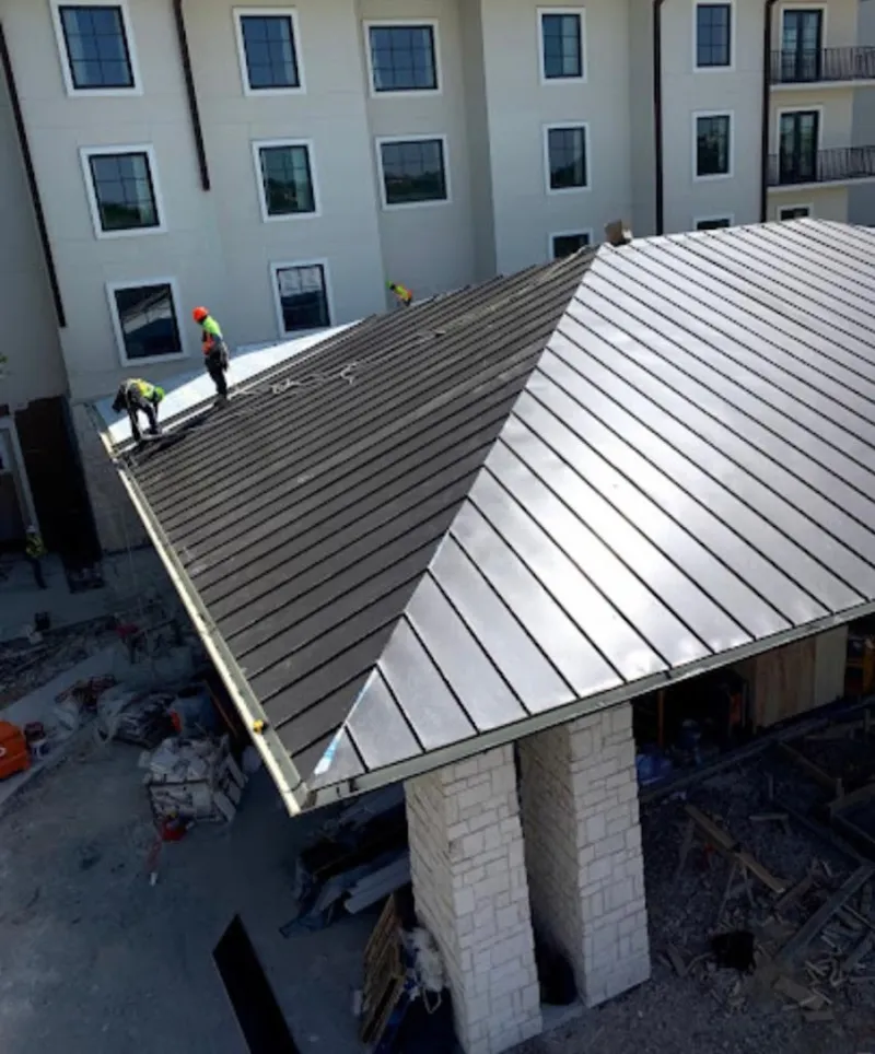Crew installing standing seam metal roof panels on a commercial project in Carnegie